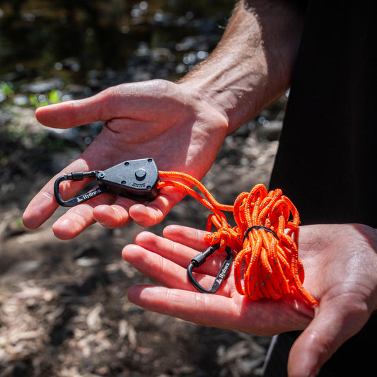 Orange Hydrava camping tensioner in hand.