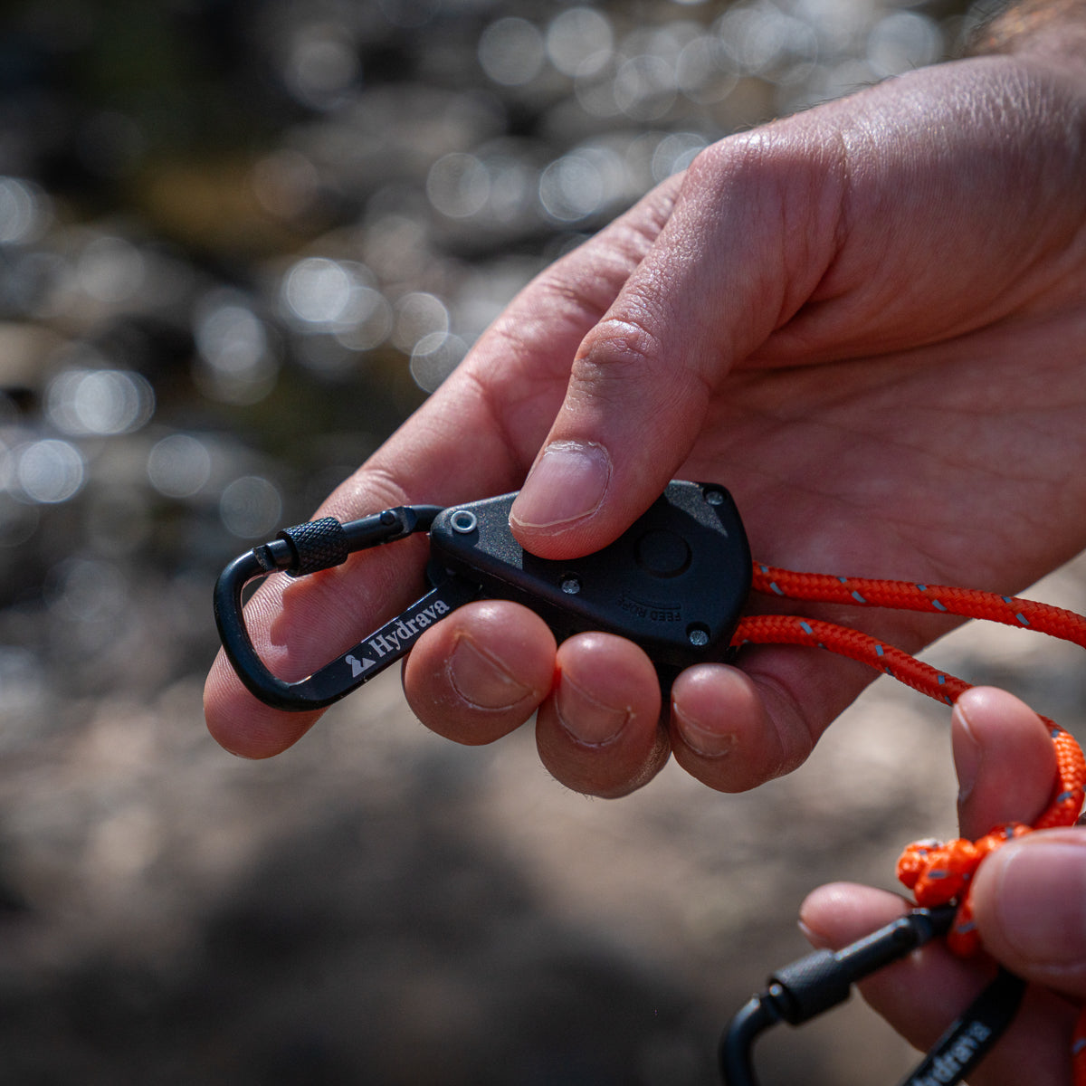 Orange Hydrava camping tensioner in hand.