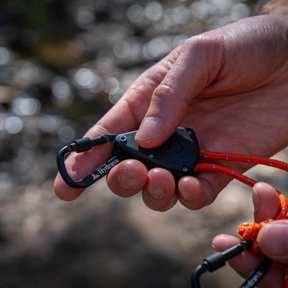 Orange Hydrava camping tensioner in hand.